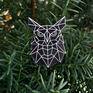 Black owl shaped refective badge with geometric pattern on a green background